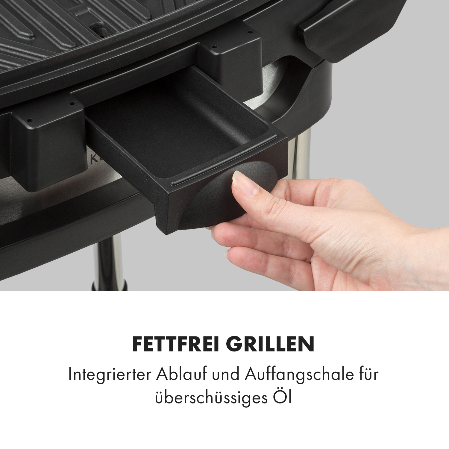 Nahaufnahme einer Hand, die einen schwarzen Grill mit herausnehmbarer Ölauffangschale benutzt.