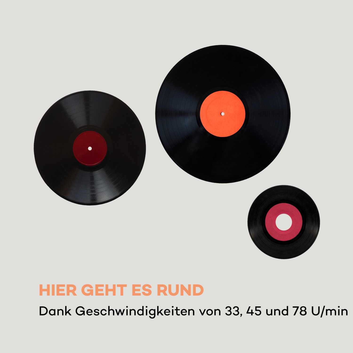 Drei Schallplatten, zwei schwarz und eine mit orangefarbener Mitte, auf beigem Hintergrund.
