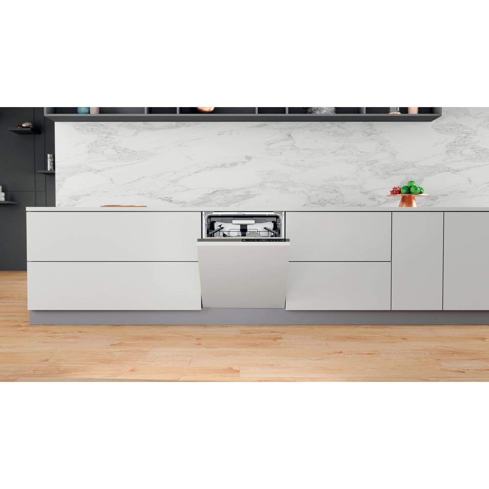 Vaatwasser met open deur, geïnstalleerd in een keuken met witte kasten en lichte houten vloer.