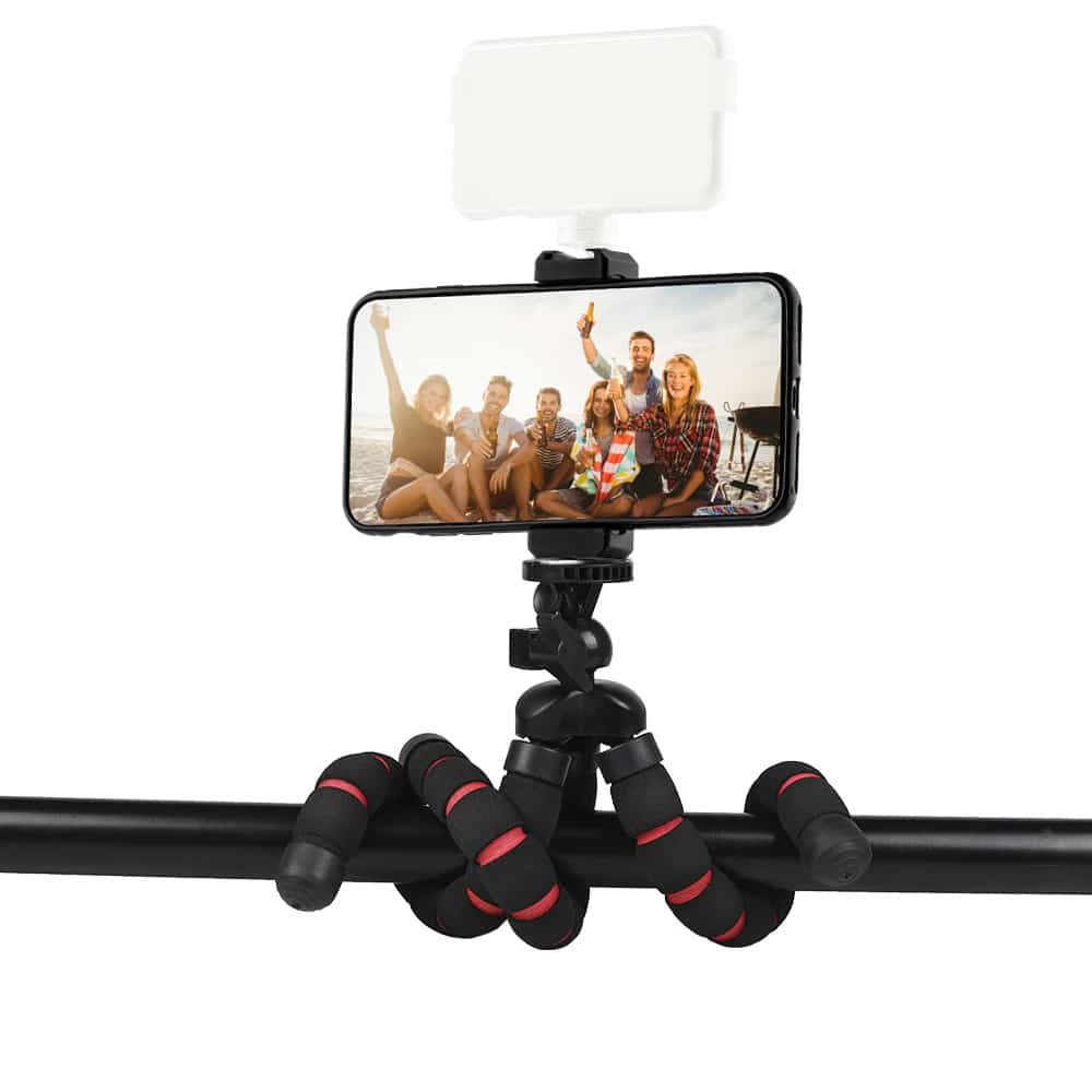 A phone on a flexible tripod is filming a group of people at the beach.