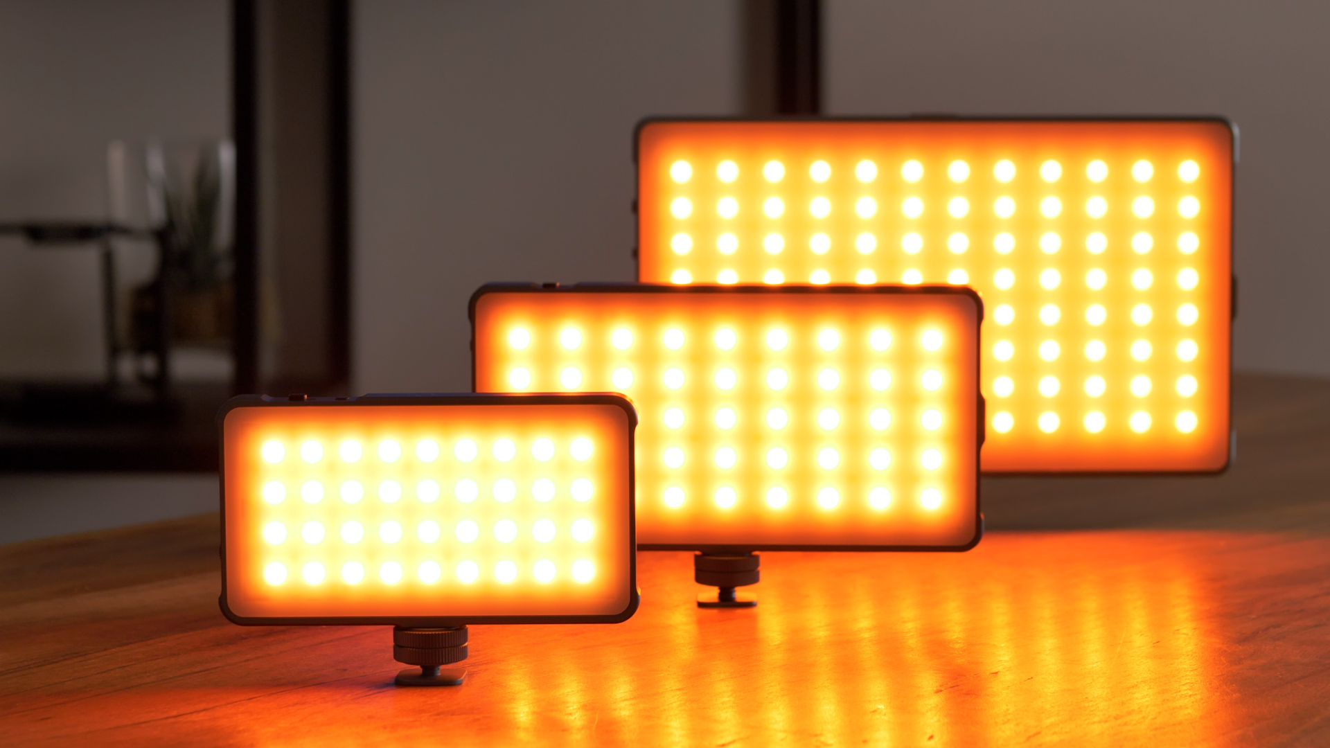 Drie LED-lampen op een houten oppervlak. Ze hebben verschillende afmetingen en hebben allemaal dezelfde oranje gloed.