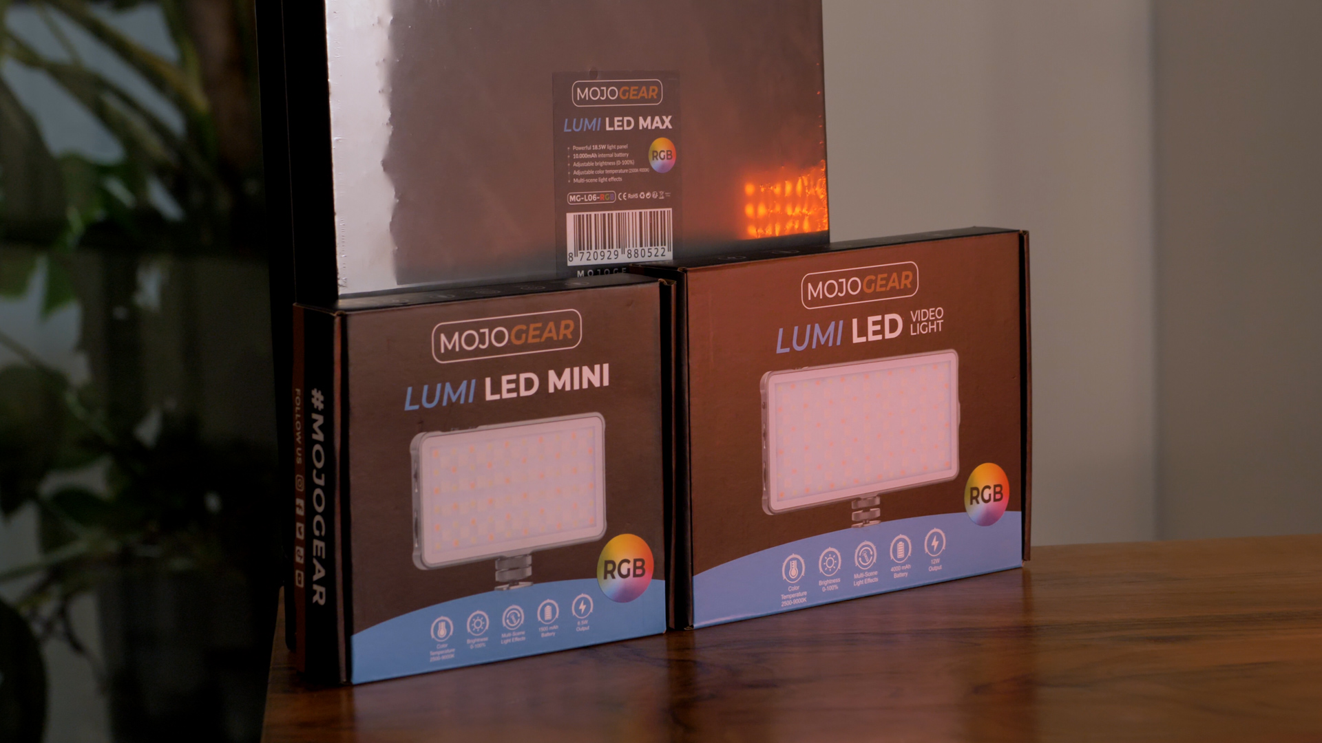 Three boxes of Lumi LED lights. MOJOGEAR branding visible. Background is a wooden table.