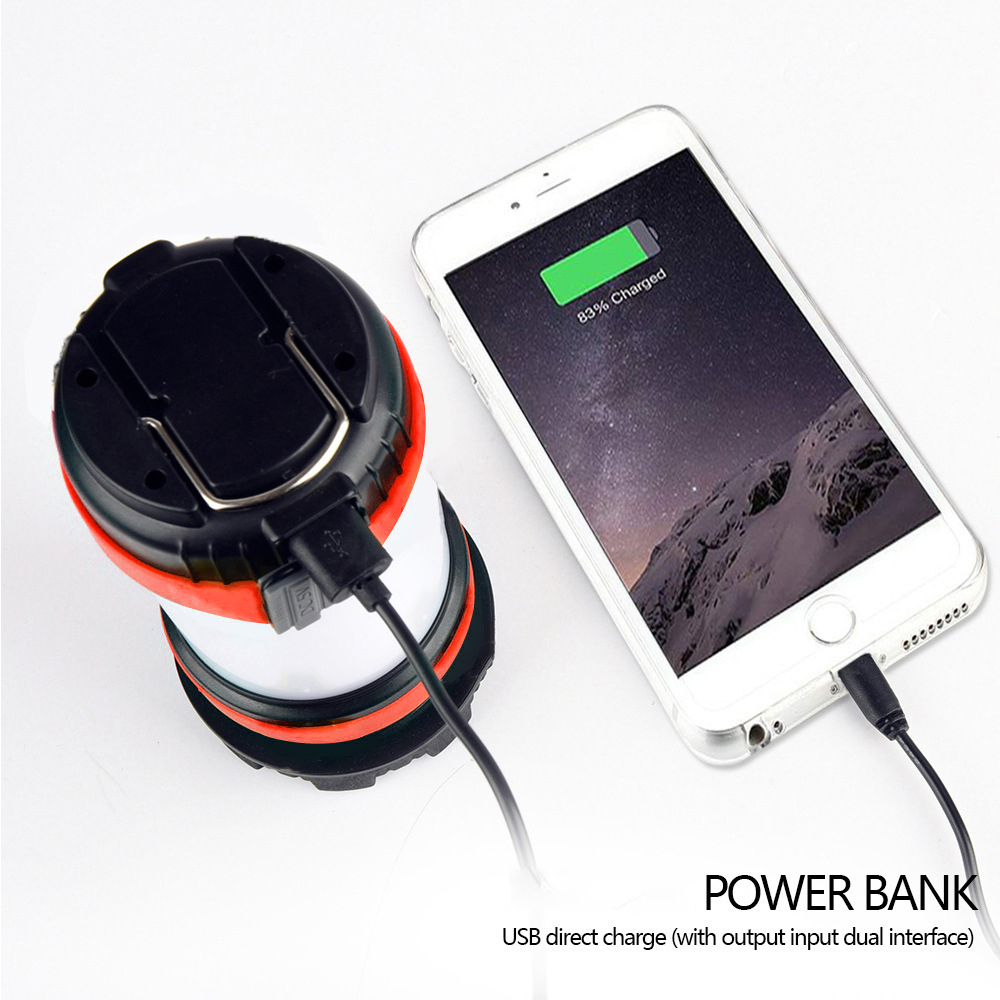 Eine schwarz-rote Laterne neben einem Telefon, das mit einer Powerbank geladen wird. Weißer Hintergrund.