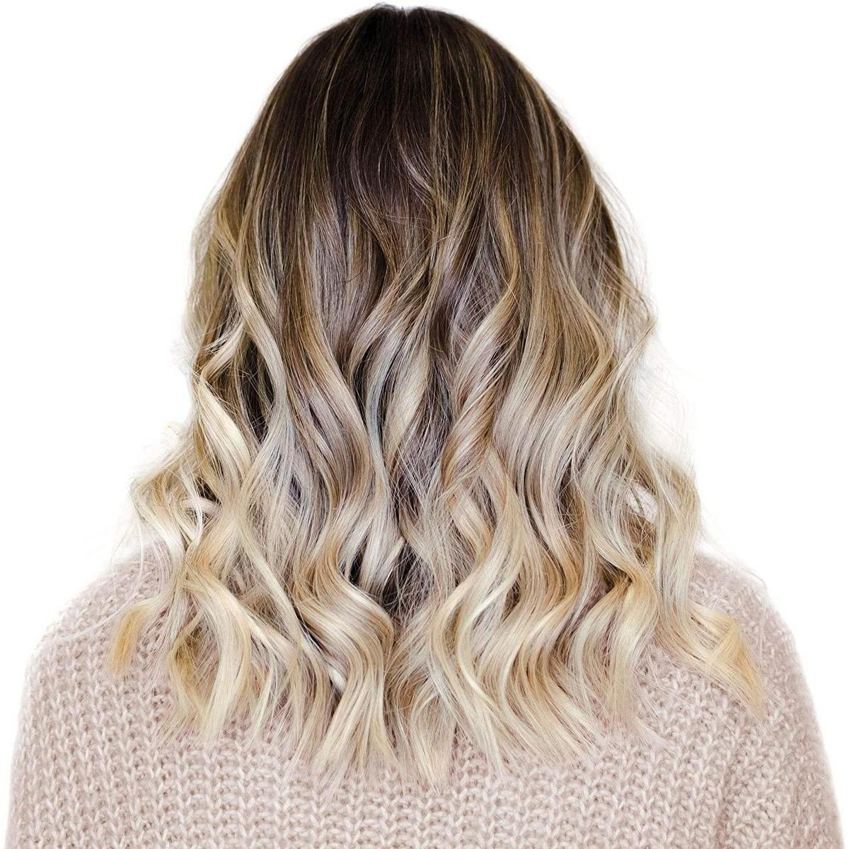 Welliges blondes und braunes Haar einer Frau, gestylt mit einem beigen Pullover.