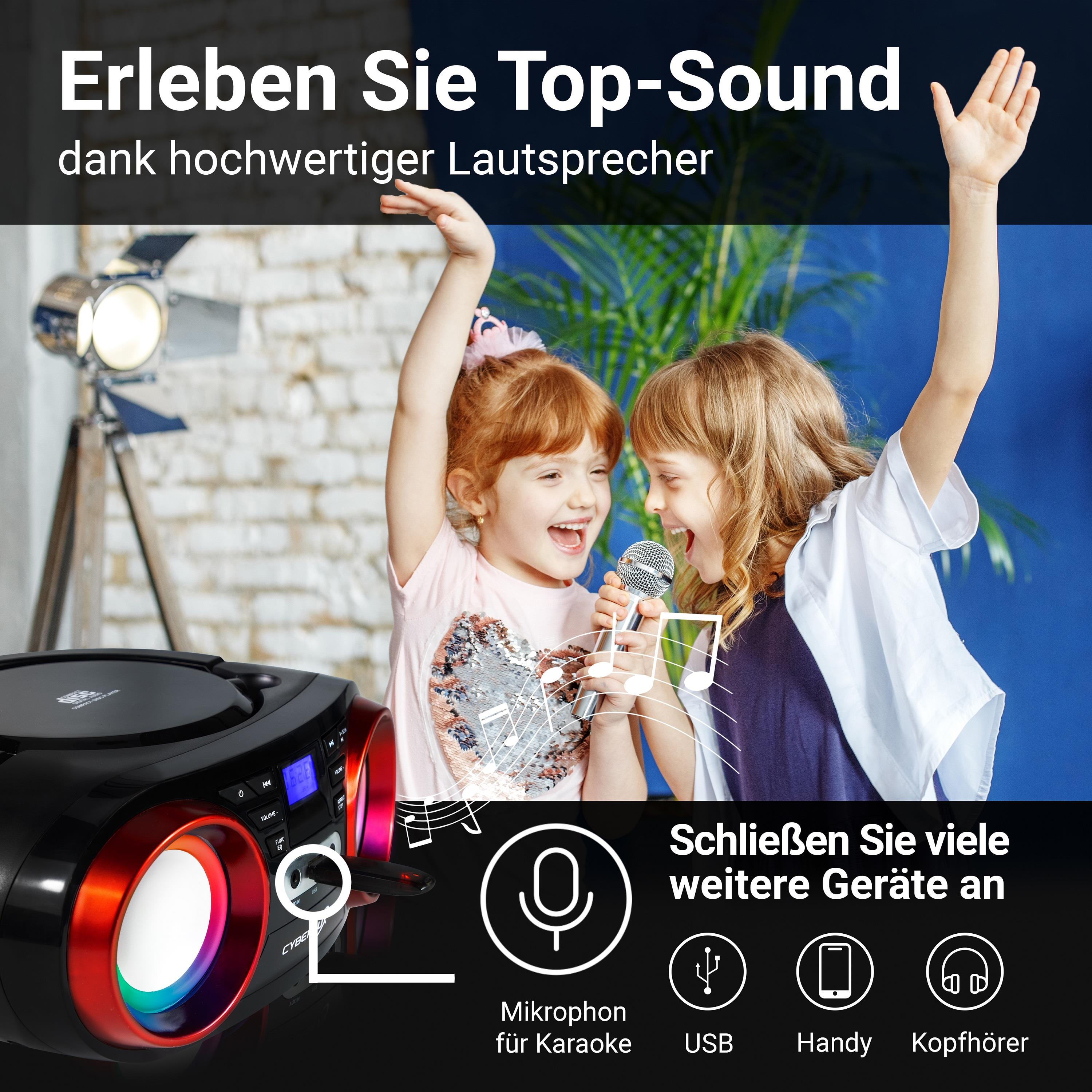 Zwei Mädchen singen in ein Mikrofon, eine Karaoke-Maschine im Vordergrund, blauer Hintergrund.