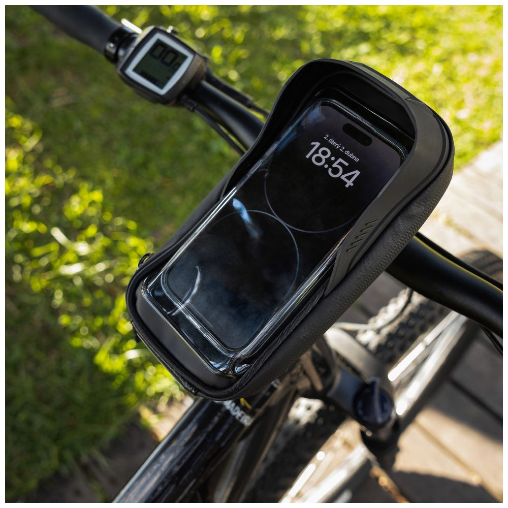 Eine schwarze Handyhülle am Fahrradlenker. Das Telefon zeigt 18:54 an. Der Hintergrund ist eine grasbewachsene Fläche.
