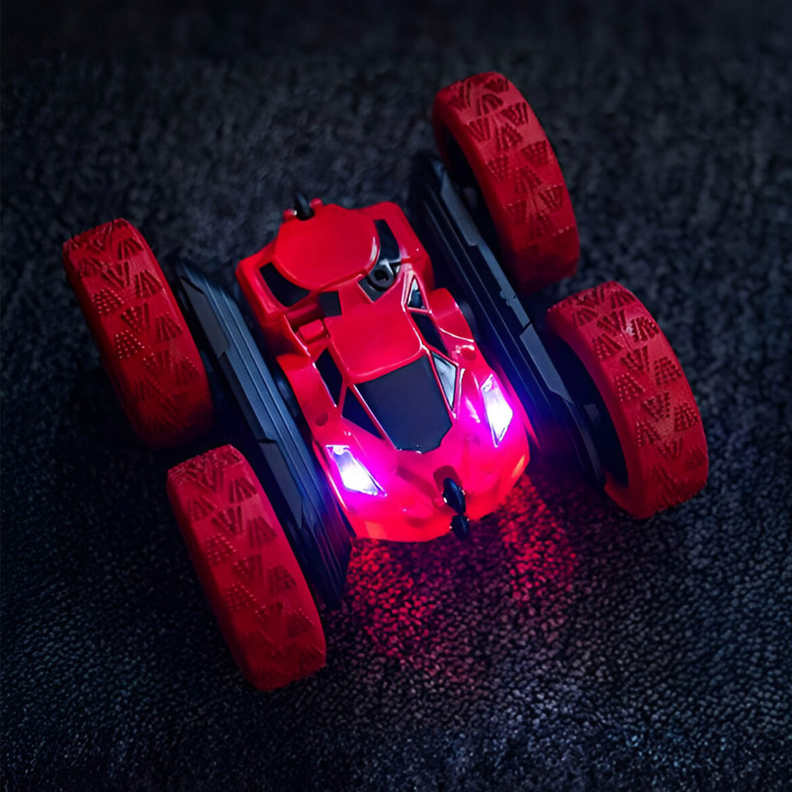 Rotes Spielzeugauto auf dunkler Oberfläche. Das Auto hat vier Räder und Lichter.