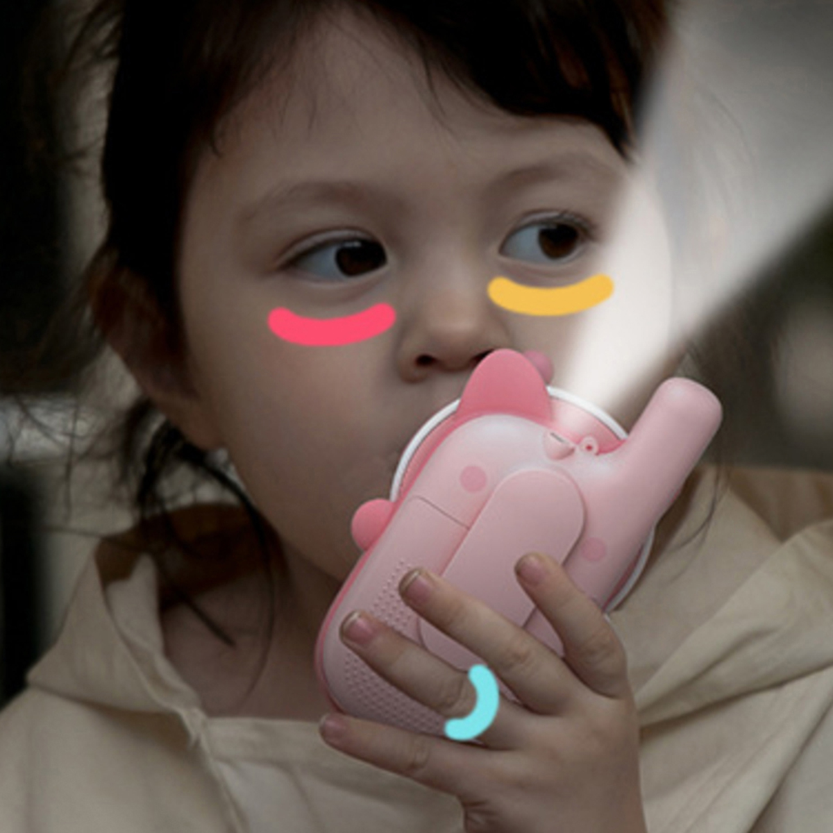 Bambina usa un telefono giocattolo rosa. Luci intorno al viso, bocca e un dito.