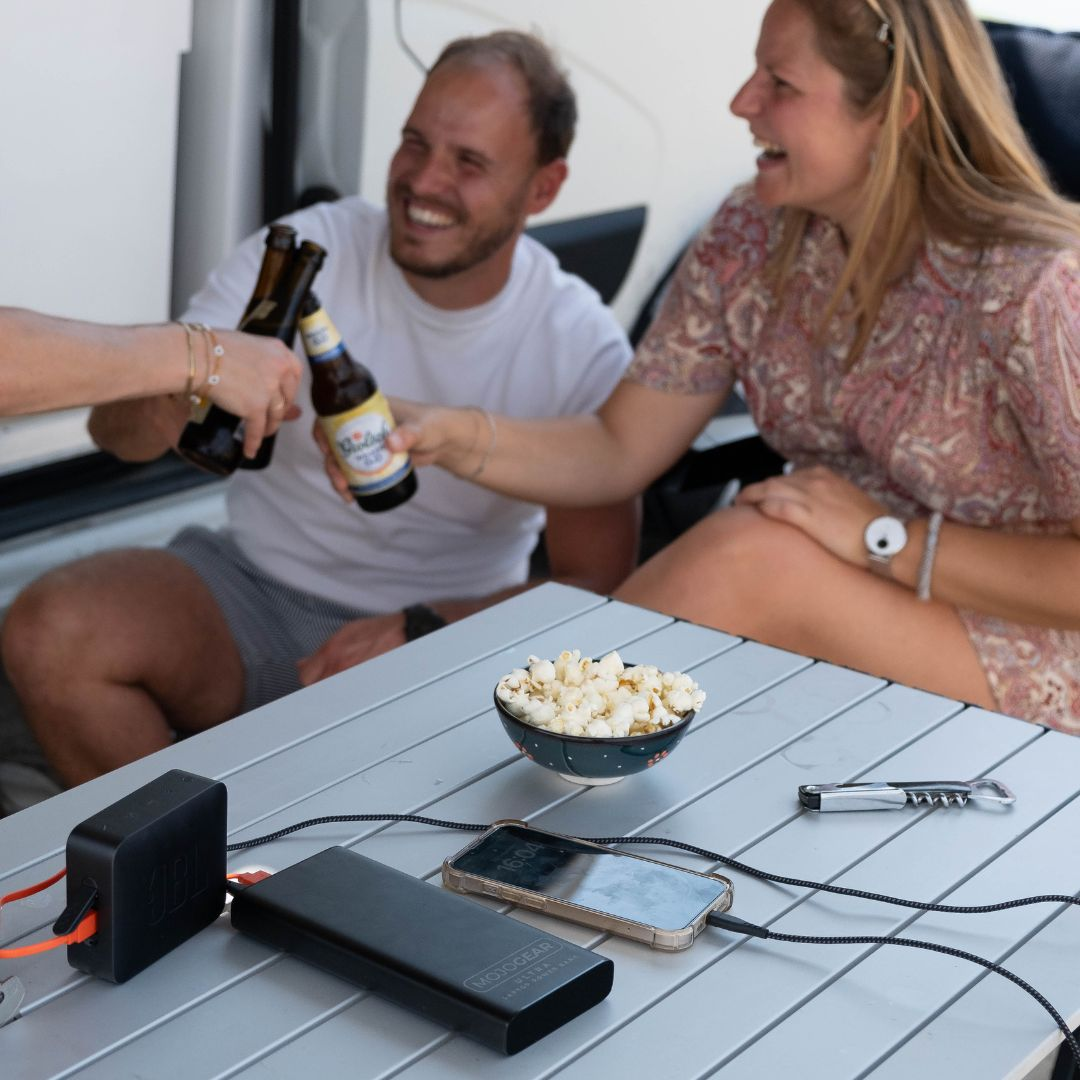 Mensen proosten met bierflessen, snacks op een tafel.