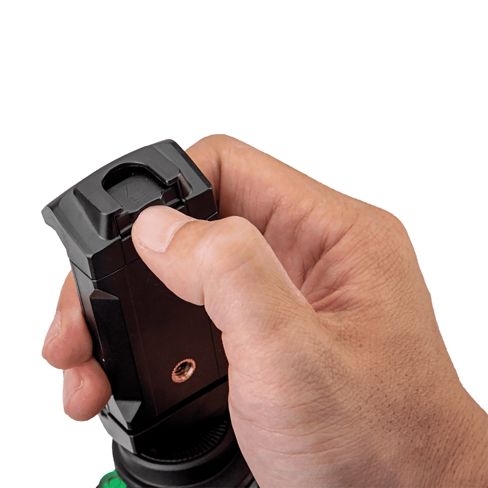 Une main tenant un objet noir. L'objet est un petit appareil avec un bouton et un dessus en forme de lentille.