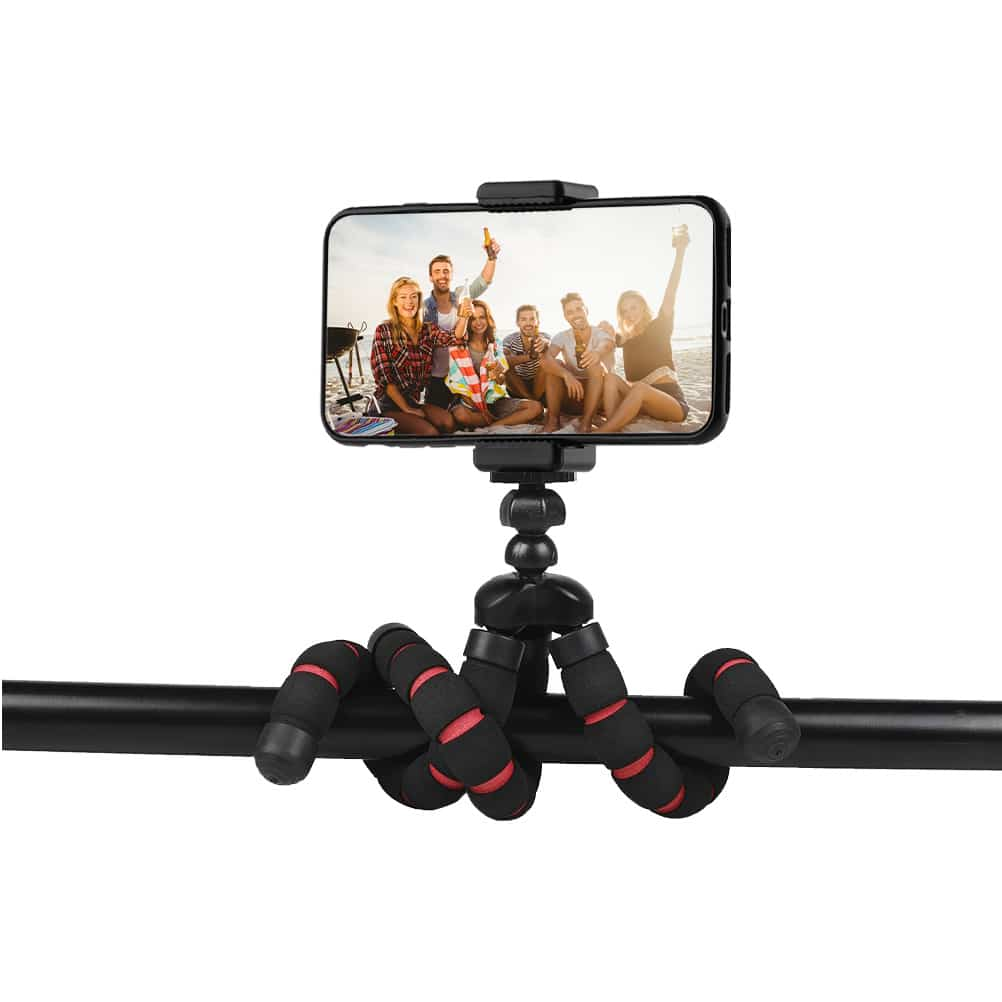 A phone on a flexible tripod, with a group of friends on a beach. A cheerful scene.