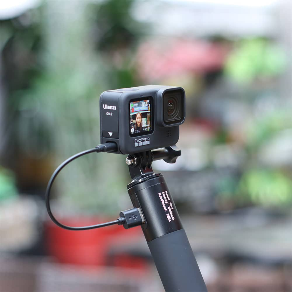 Een GoPro-camera staat op een selfiestick. De camera toont een vrouw op het scherm.