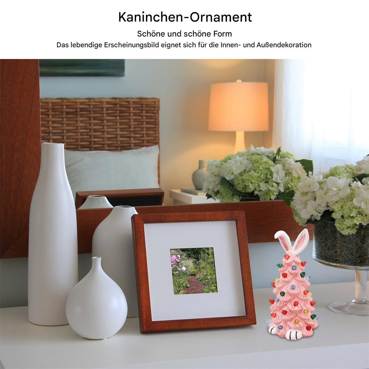 Ein pinker Hasen-Weihnachtsbaum mit Lichtern auf einem weißen Tisch. Andere Dekorationen vorhanden.