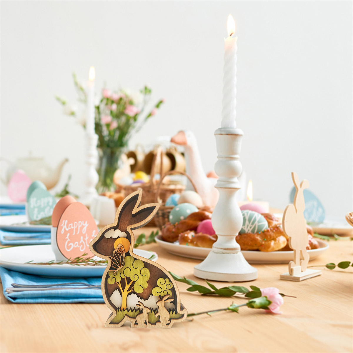 Ostern Tisch. Holzhasen-Dekor, Kerzen, Eier und Essen auf einem Holztisch.