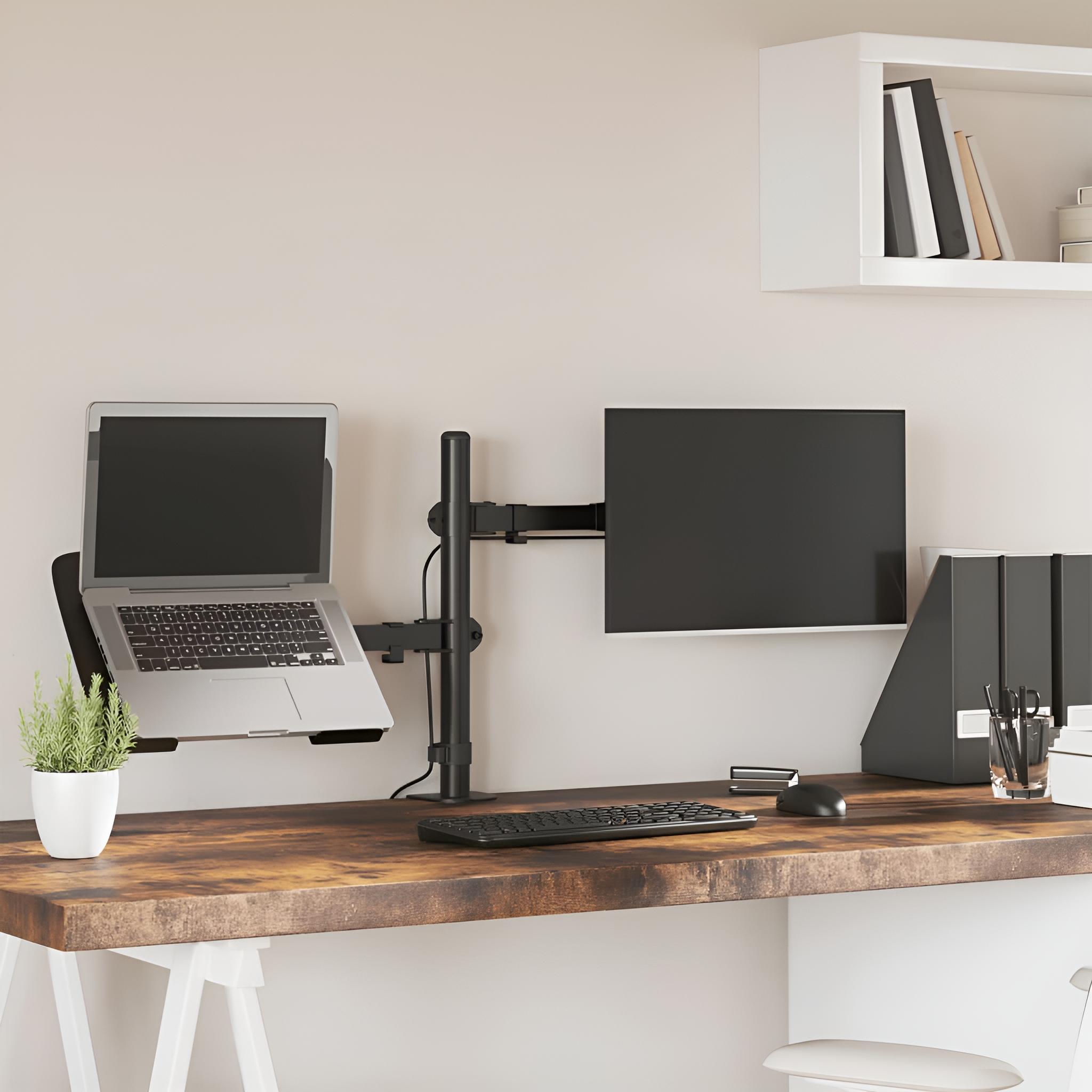 Schreibtisch mit Laptop, Monitor, Tastatur, Maus und Pflanze, mit weißer Wand.