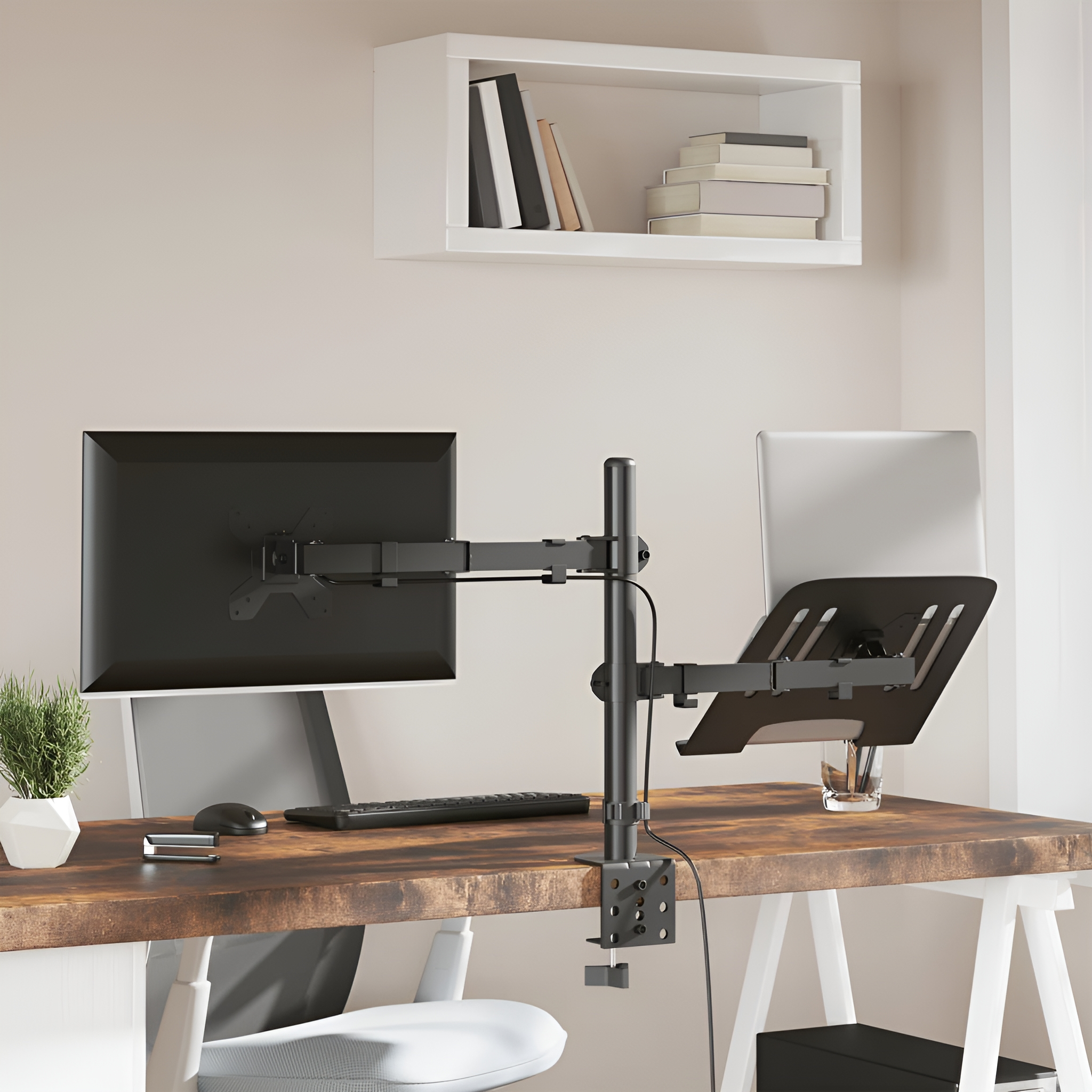 Schreibtisch mit Computermonitor, Laptopständer, Stuhl. Ein weißes Regal mit Büchern darüber.