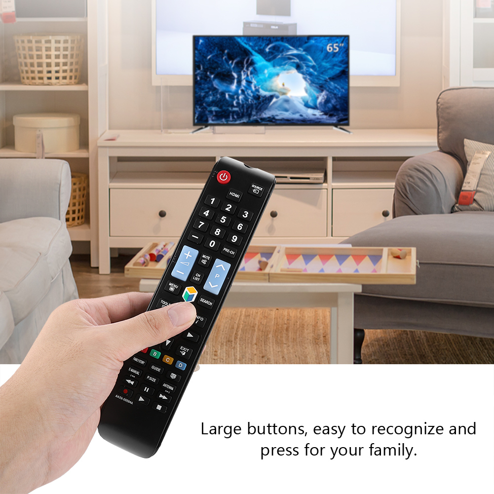 Hand hält schwarze TV-Fernbedienung, große Tasten, TV im Hintergrund.
