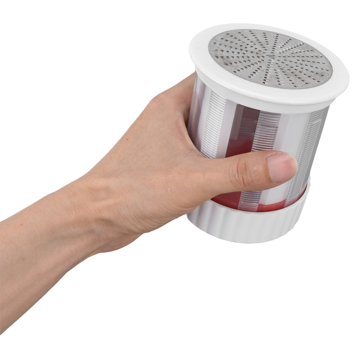 Eine Hand, die einen weißen und roten Behälter mit einer Reibefläche oben hält.