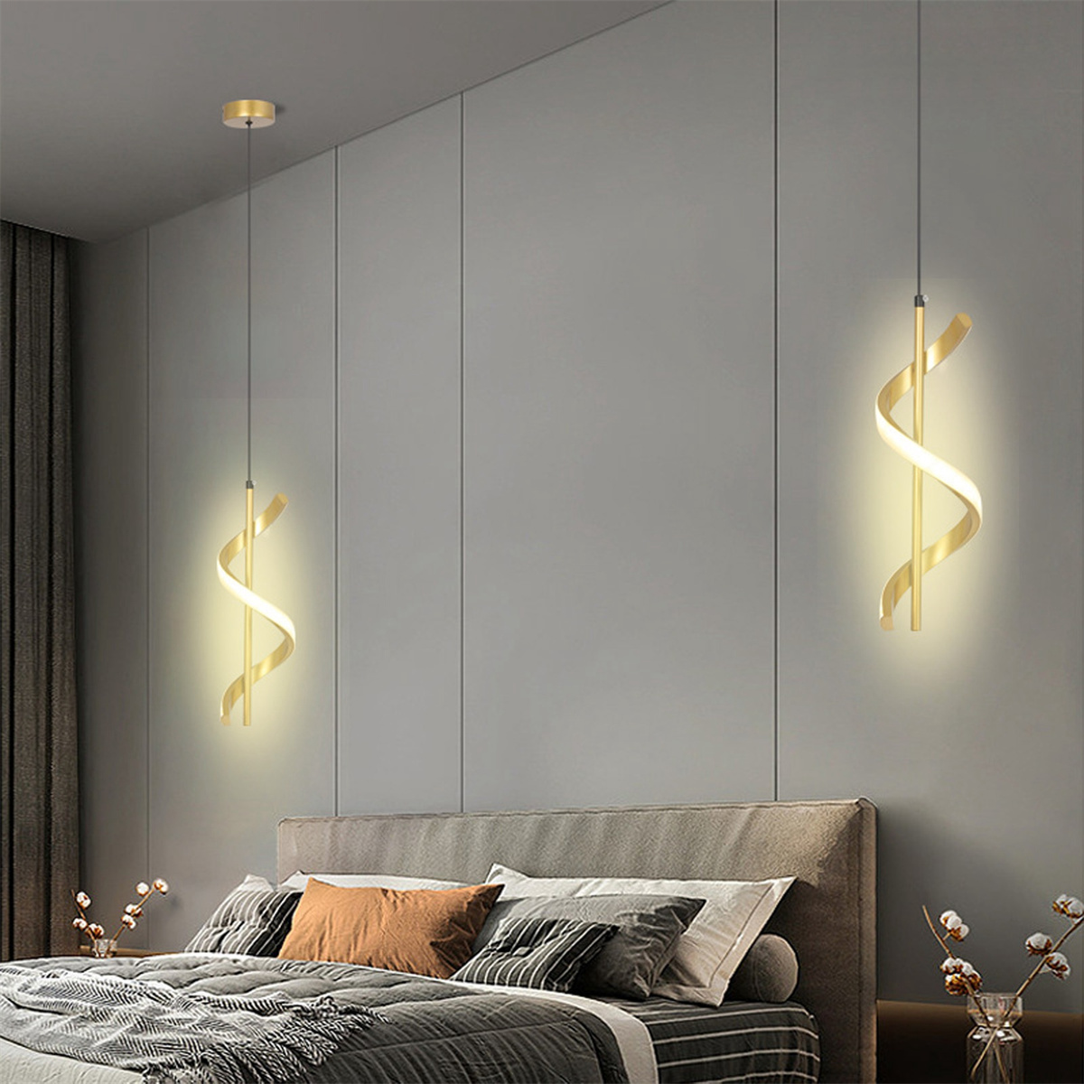 Zwei goldene Spiral-Pendelleuchten hängen von der Decke. Grauer Wandhintergrund, darunter ein Bett sichtbar.