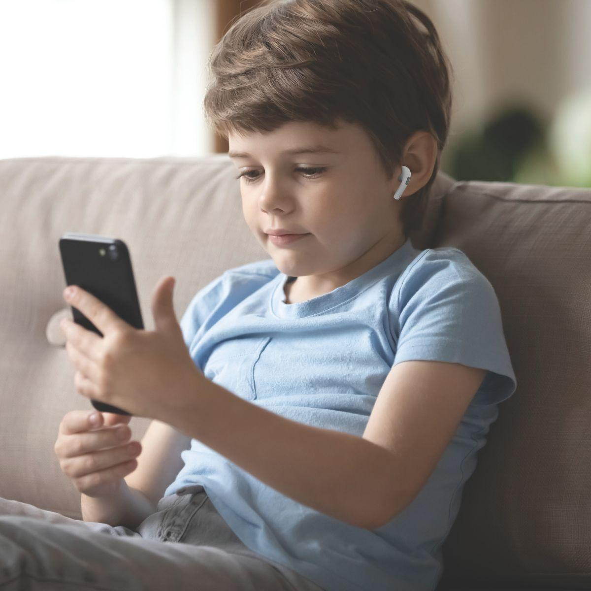 Ein junger Junge benutzt ein schwarzes Smartphone mit weißen Ohrhörern.