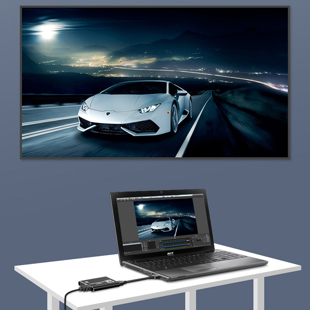 Laptop, der mit einem Display verbunden ist, das ein Auto auf einer Straße zeigt. Schreibtisch und blaue Wand im Hintergrund.