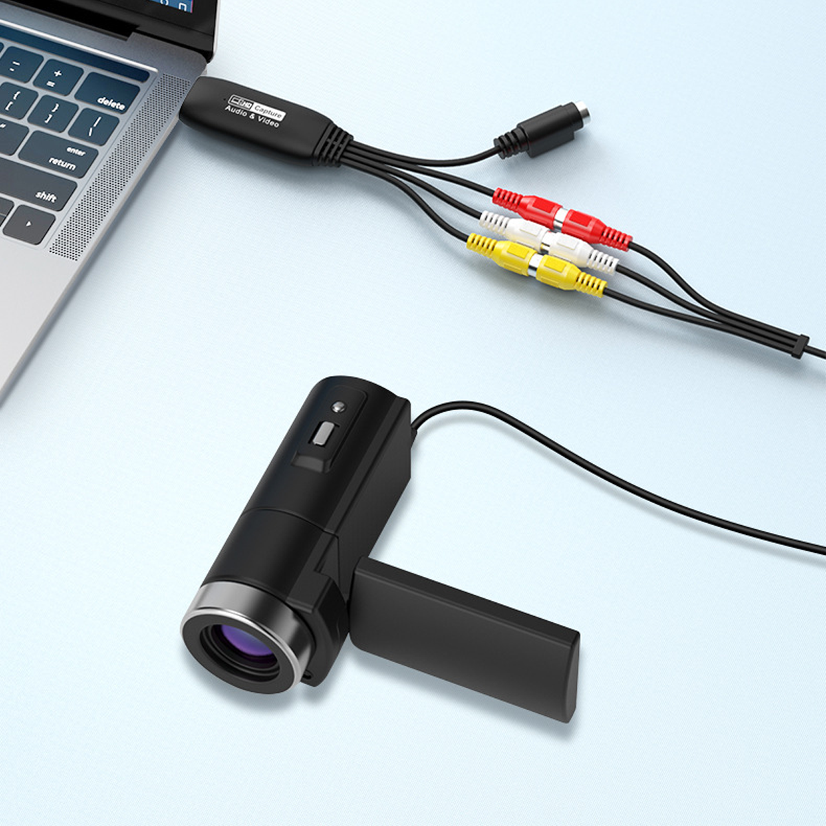 Ein Laptop, der mit einem schwarzen Adapter verbunden ist, mit Kabeln, die zu einer schwarzen Kamera und anderen Anschlüssen führen.