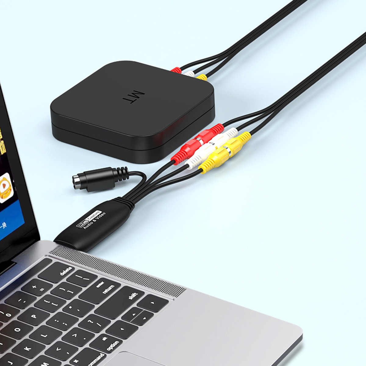 Ein Laptop, der über farbige AV-Kabel mit einer schwarzen Box verbunden ist, auf hellblauem Untergrund.
