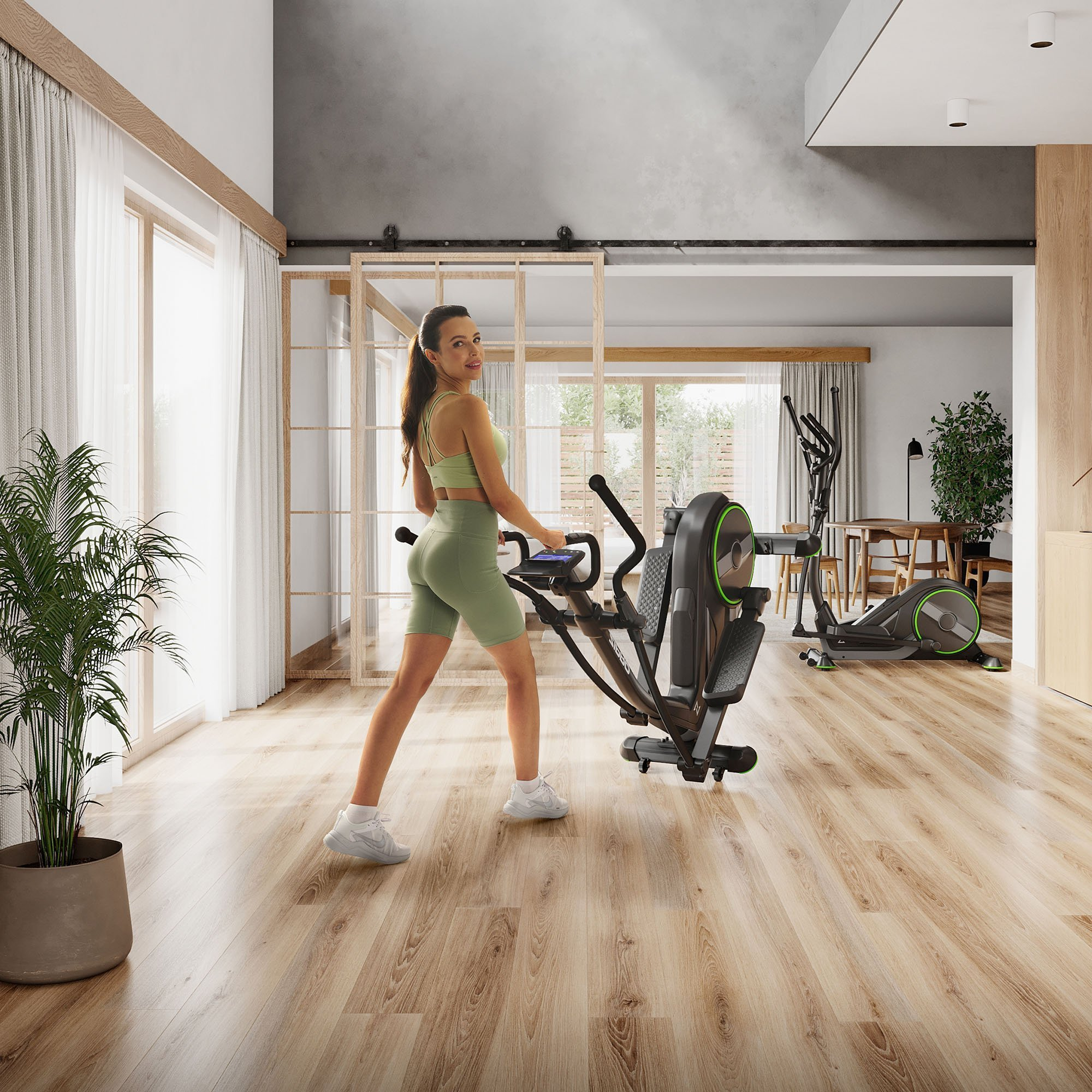 Eine Frau trainiert auf einem Crosstrainer in einem modernen, gut beleuchteten Fitnessstudio zu Hause.