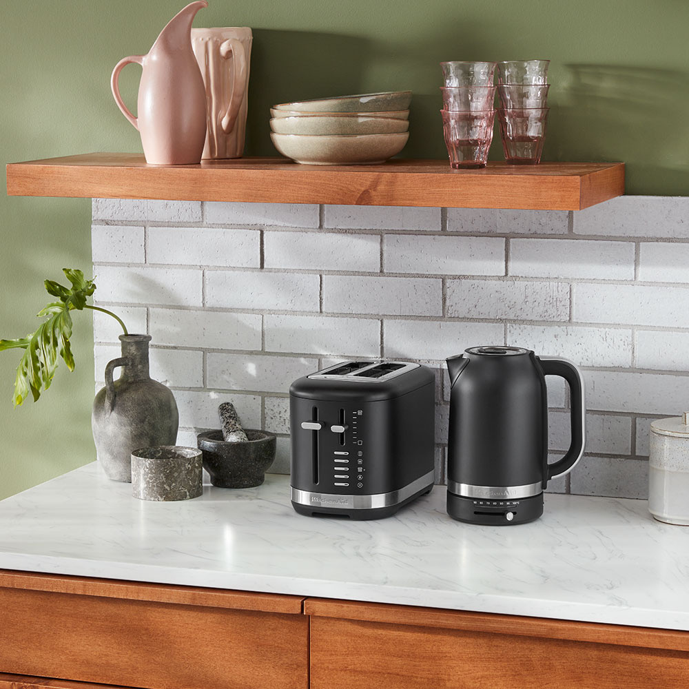 Ein schwarzer Toaster und Wasserkocher auf einer Marmorarbeitsplatte, mit Regalen und Deko.