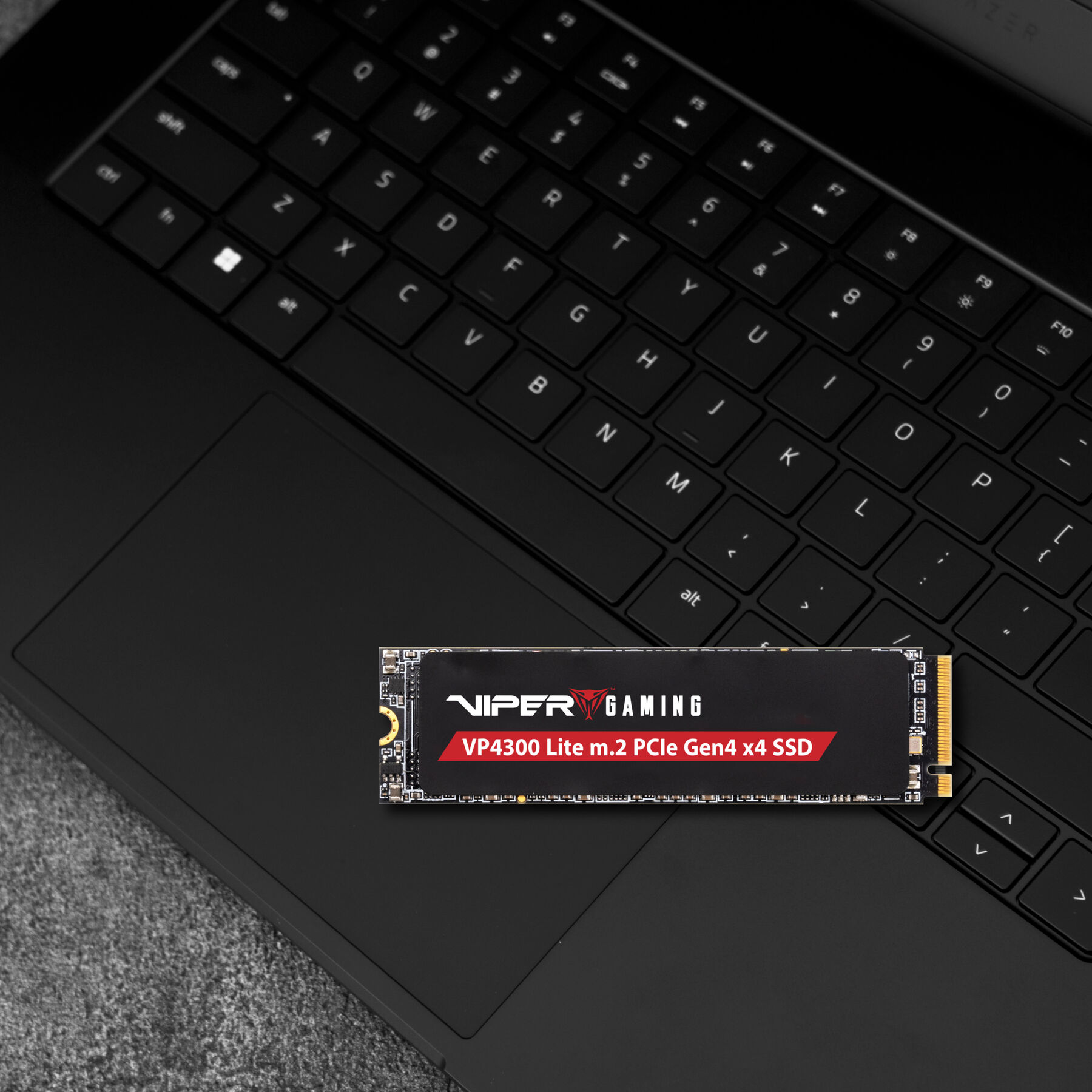 Czarny laptop z podświetloną kartą SSD na górze, wyświetlającą 'VIPER GAMING' i inne szczegóły.