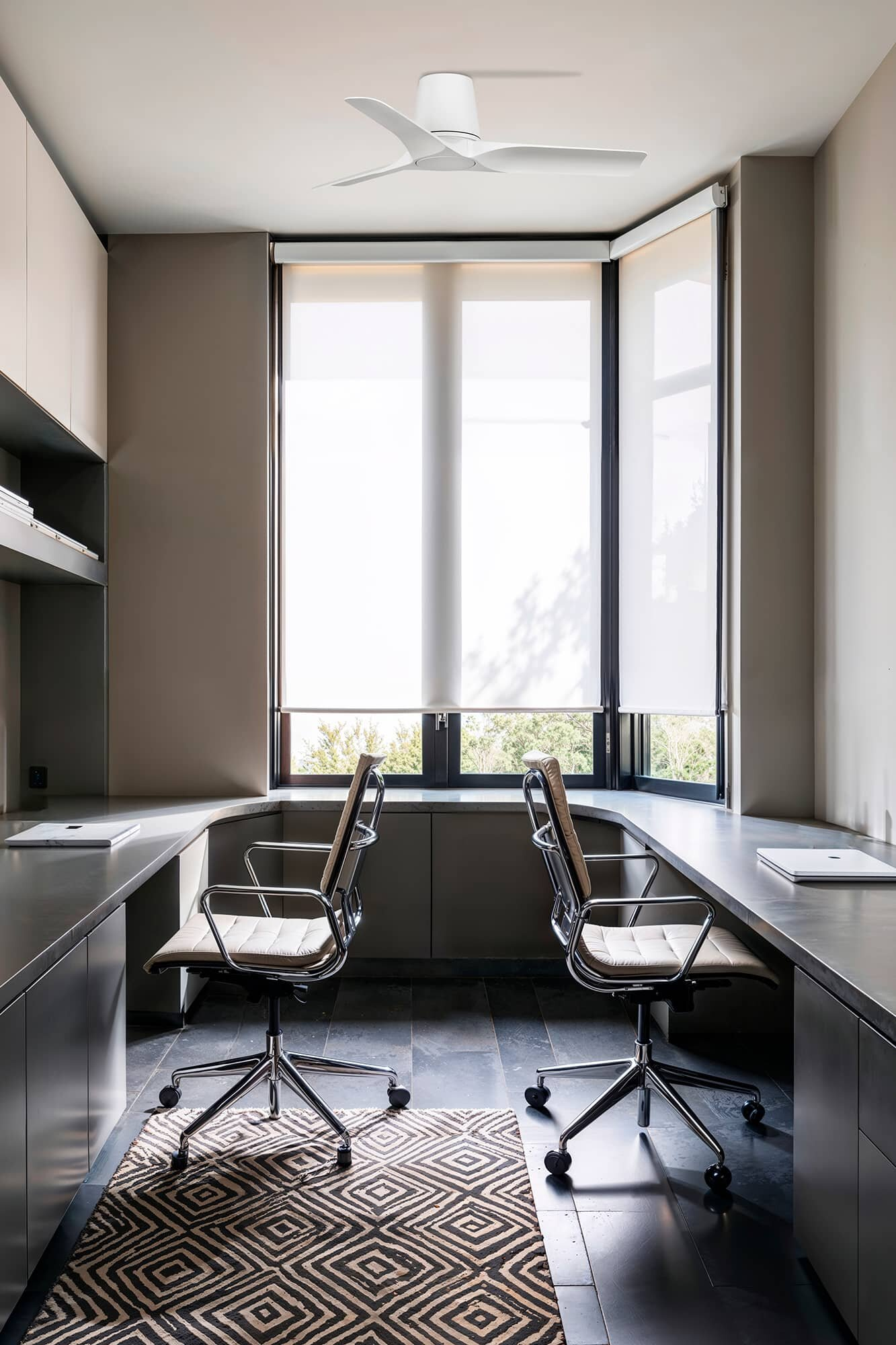 Ein Büro mit zwei Schreibtischen, Stühlen und einem großen Fenster.