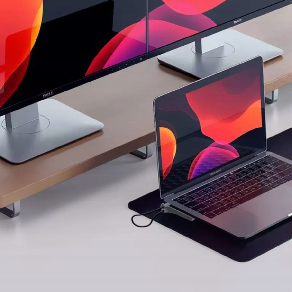 Konfiguracja laptopa, monitora i biurka. Monitor wyświetla pulpit z czerwonym i pomarańczowym tłem.