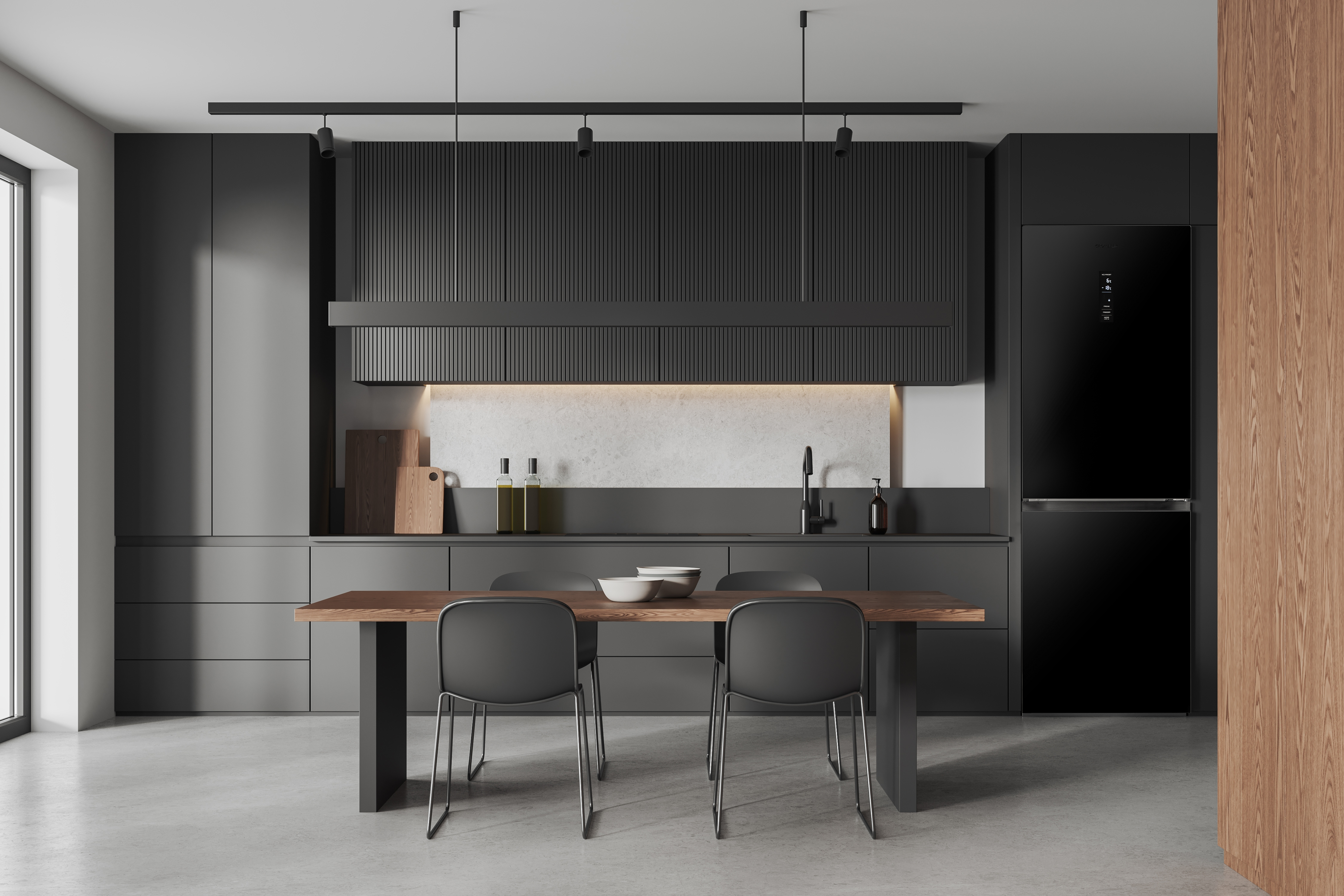 Interno cucina moderna con mobili grigio scuro, tavolo in legno e frigorifero nero.