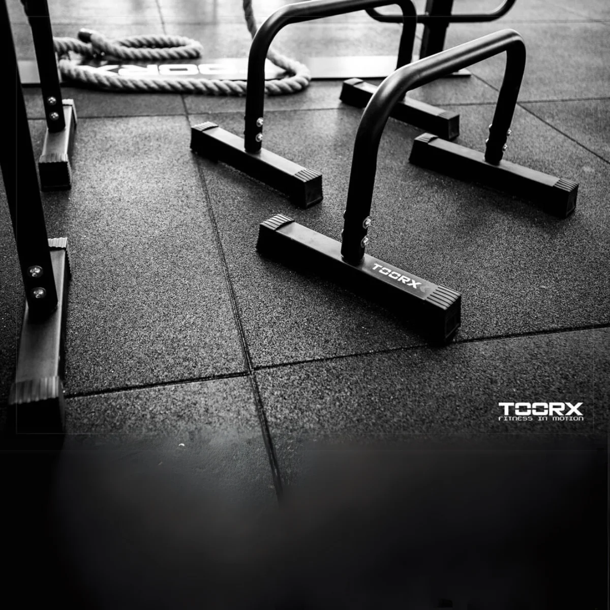Parallelle bars in een sportschool. Donker, zwart-wit. De vloer is zwart met tegels.