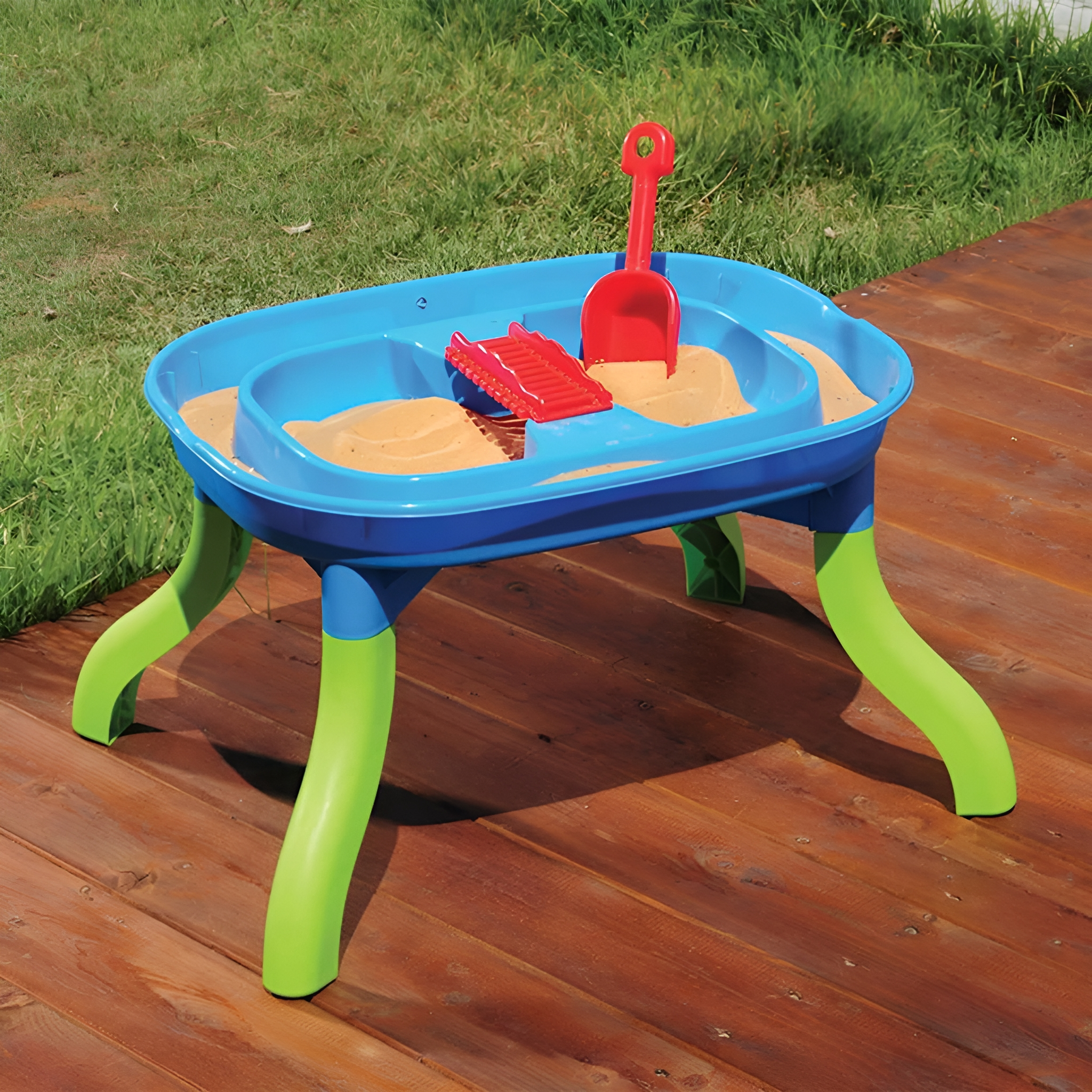 Blauer und grüner Sandkasten mit Sand und roter Schaufel und Rutsche.