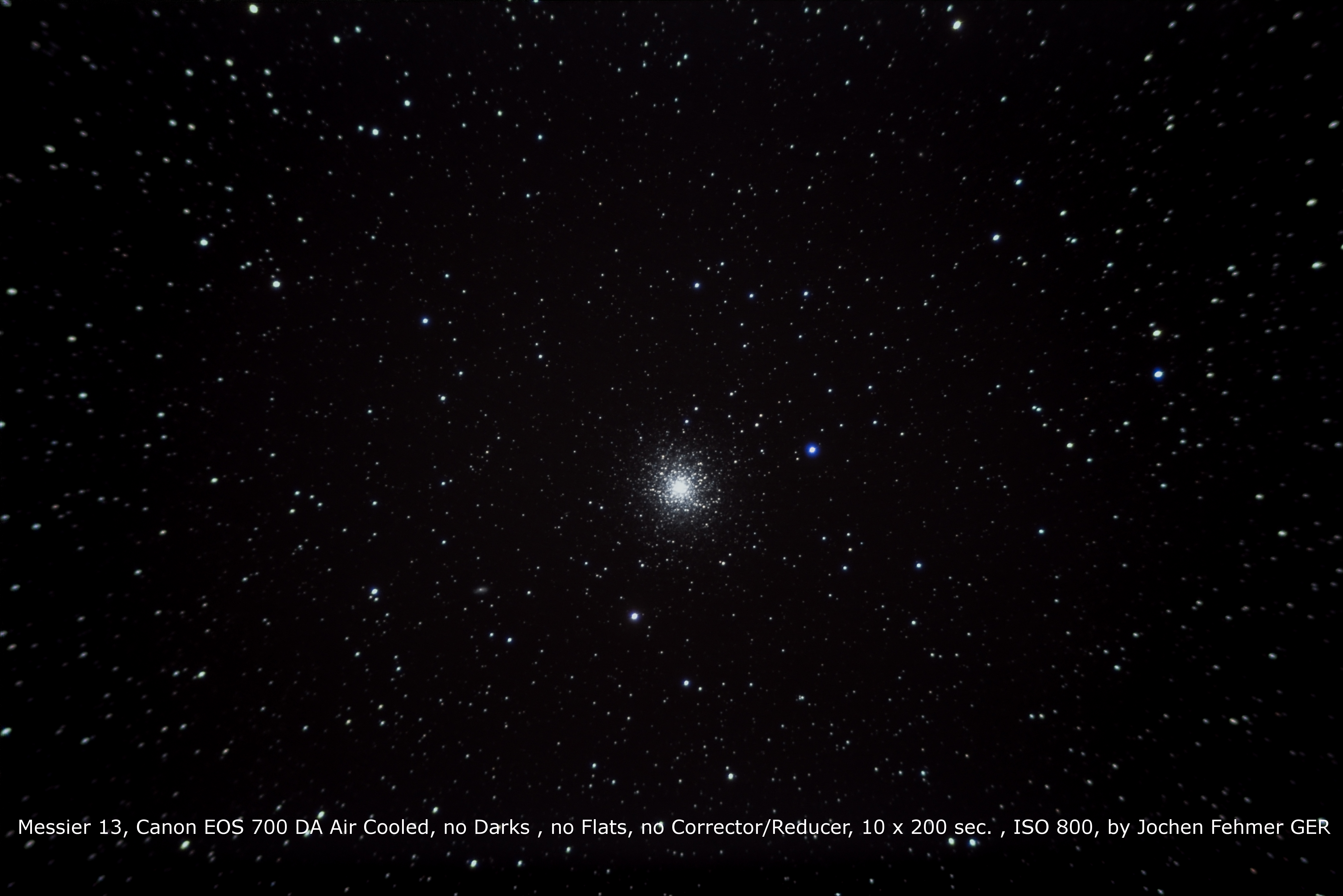 Un campo estelar con un cúmulo brillante en el centro. Numerosas estrellas blancas sobre fondo negro.