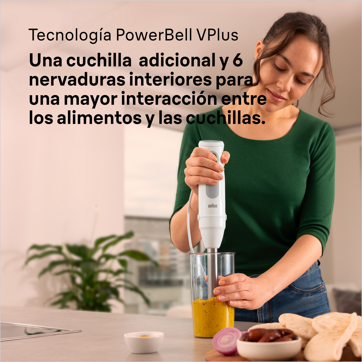 Kobieta używająca białego blendera ręcznego w szklance, mieszająca żółtą substancję.