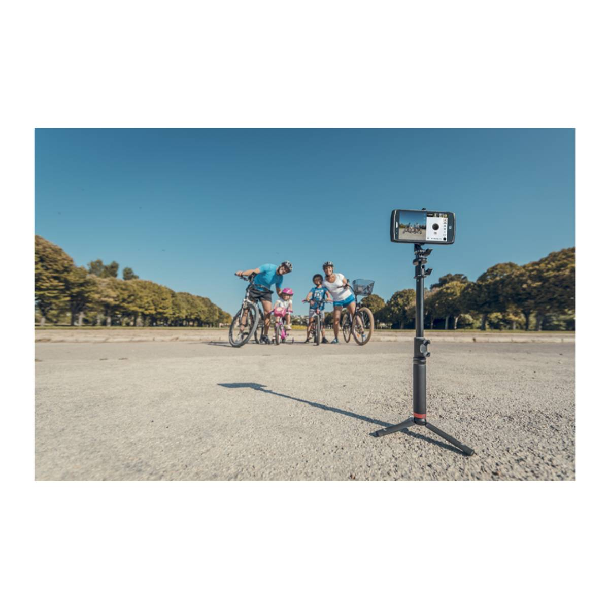 Una famiglia con biciclette e un bastone per selfie con un telefono che li riprende.