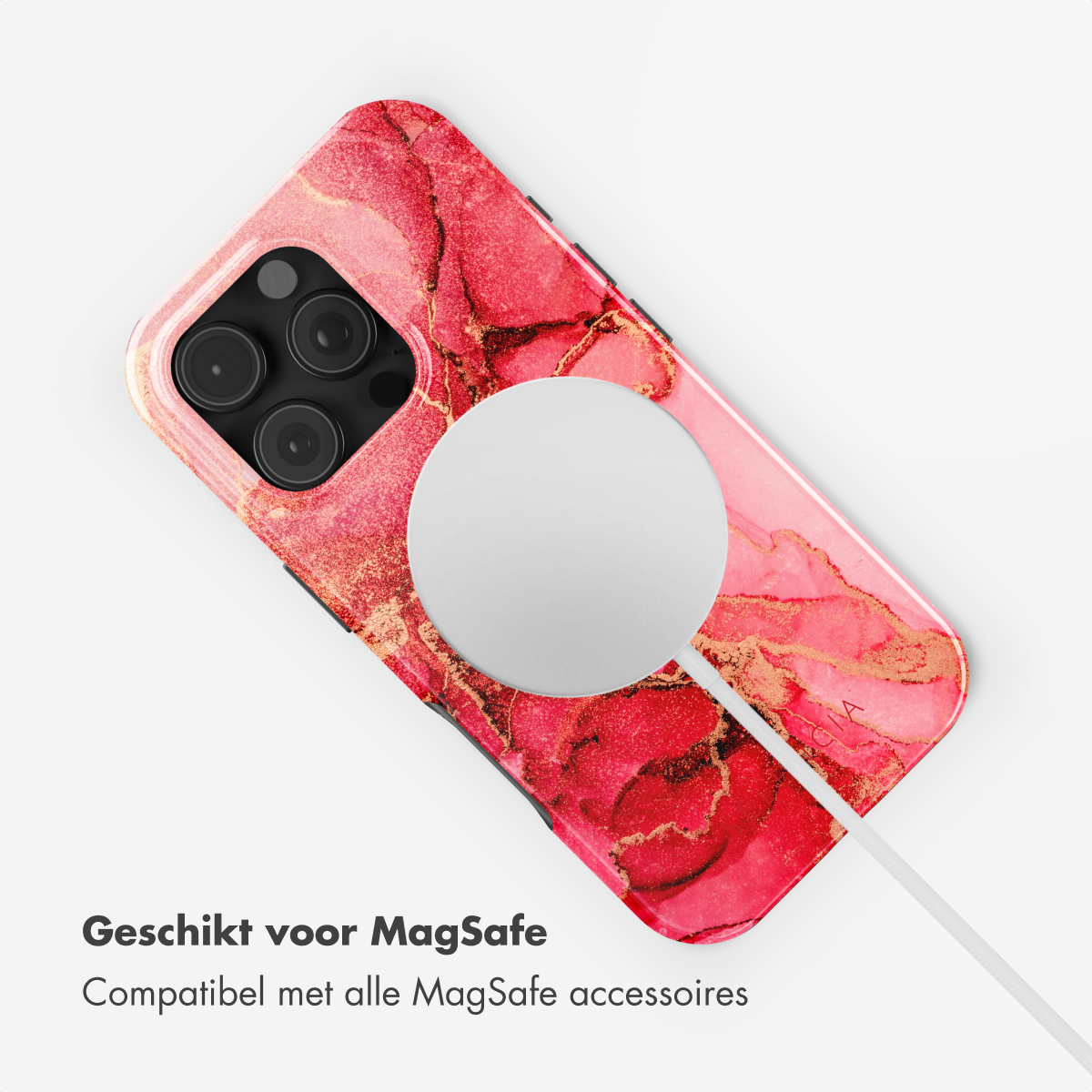 Une coque de téléphone avec un marbrage rouge et or. Un chargeur MagSafe circulaire blanc est attaché. Sur une surface blanche.