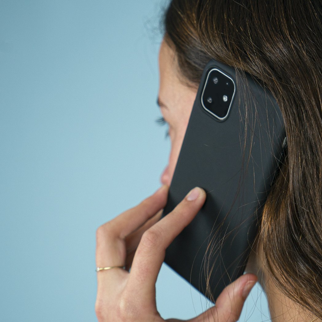 Una donna parla al telefono. Il telefono è in una custodia nera.