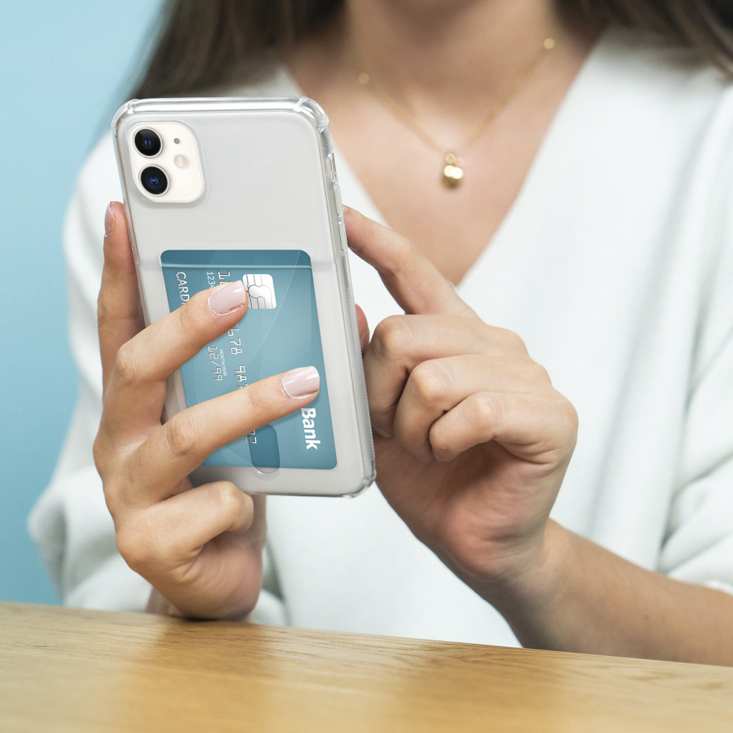 Een persoon die een telefoon vasthoudt met een doorzichtige hoes en een creditcard erin.