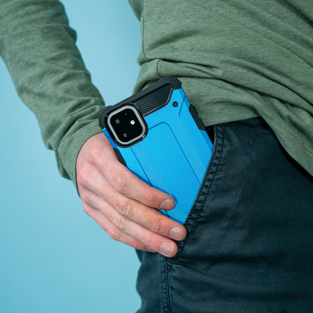 Een blauwe telefoonhoes in de zak van een persoon. De persoon draagt een groen shirt en een zwarte broek.