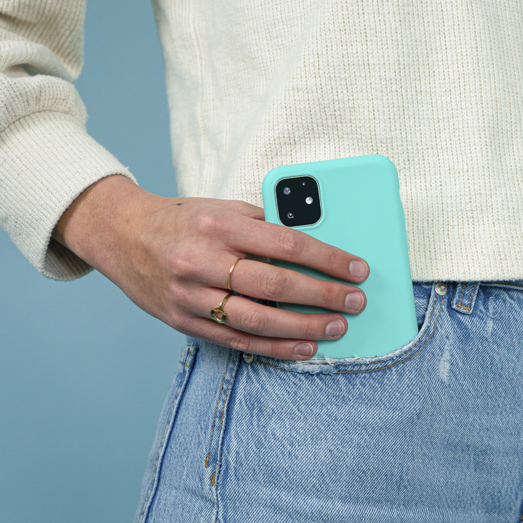 Een hand in een zak met een mintgroene telefoon, draagt een blauwe jeans.