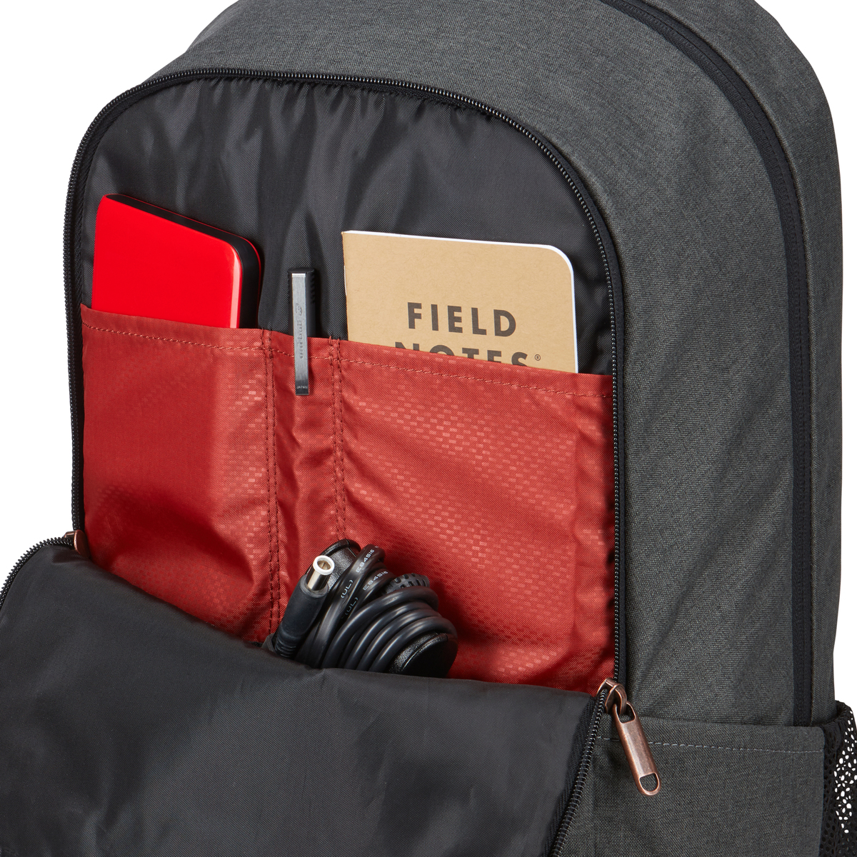 Rucksack offen mit roter Festplatte, Notizblock, Stift und Kabel.