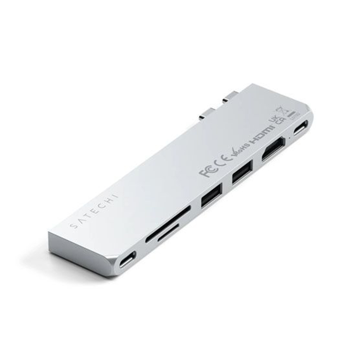 Hub USB-C plateado Satechi con puertos. Está sobre una superficie blanca.