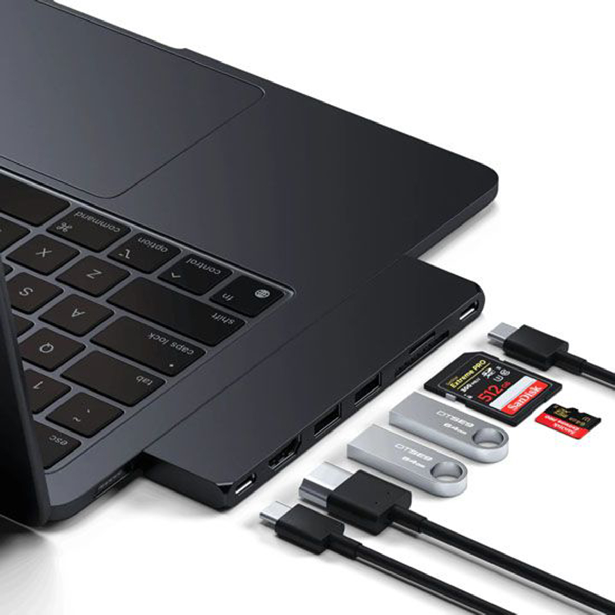 Portátil con concentrador USB-C, tarjeta SD, unidades flash y cables. Fondo blanco con accesorios.