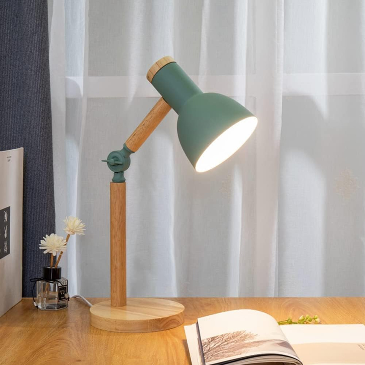 Grüne und Holz Schreibtischlampe auf einem Holztisch. Ein Buch und Blumen sind auch auf dem Tisch.