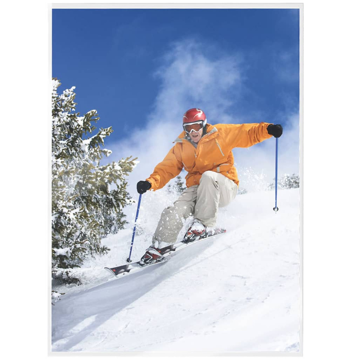 Ein Skifahrer in einer orangen Jacke und roter Brille, der eine schneebedeckte Piste unter blauem Himmel hinunterfährt.