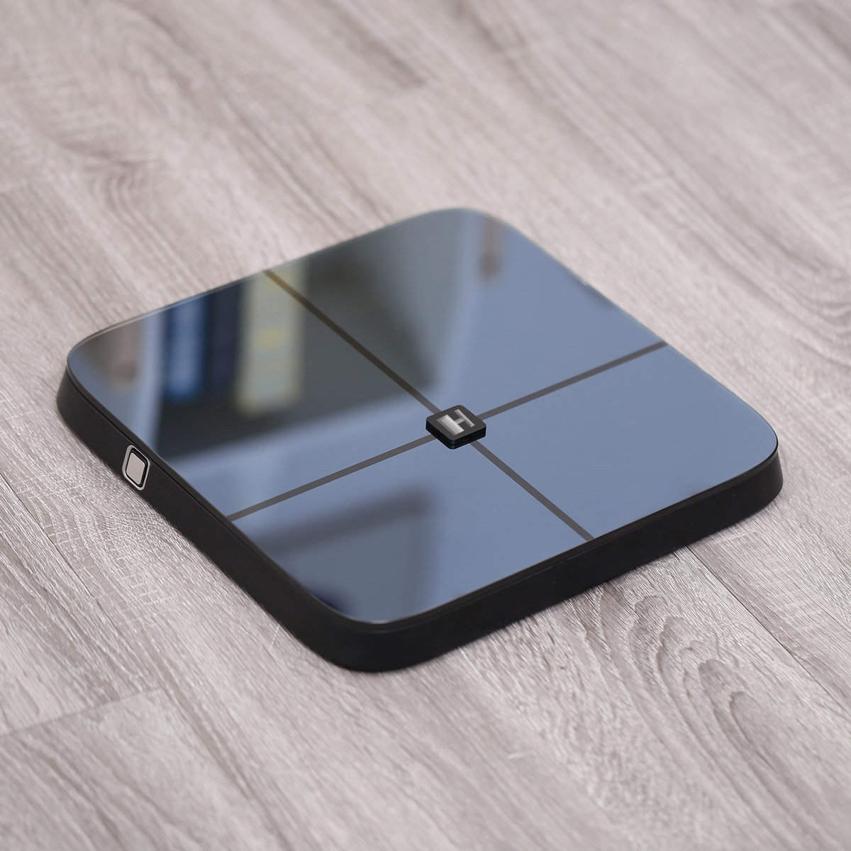 Czarna i niebieska inteligentna waga na drewnianej podłodze.
