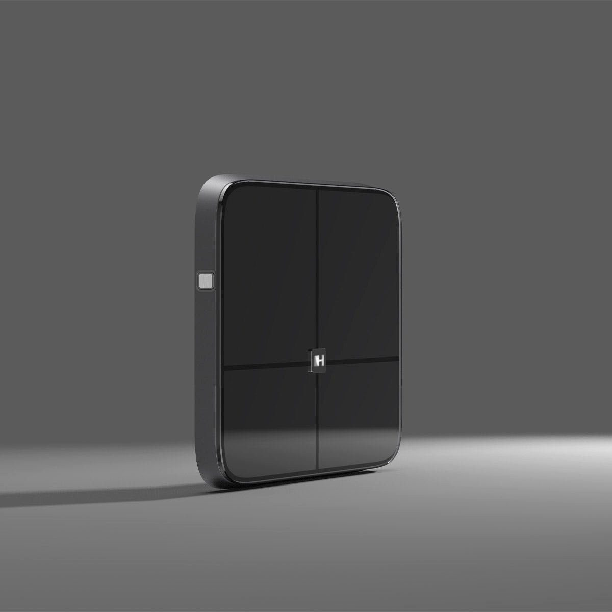 Czarne kwadratowe urządzenie. Ma jeden biały przycisk z boku i znajduje się na szarym tle.